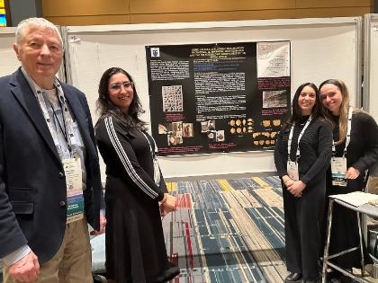 A LCW professor and three LCW students before a poster.